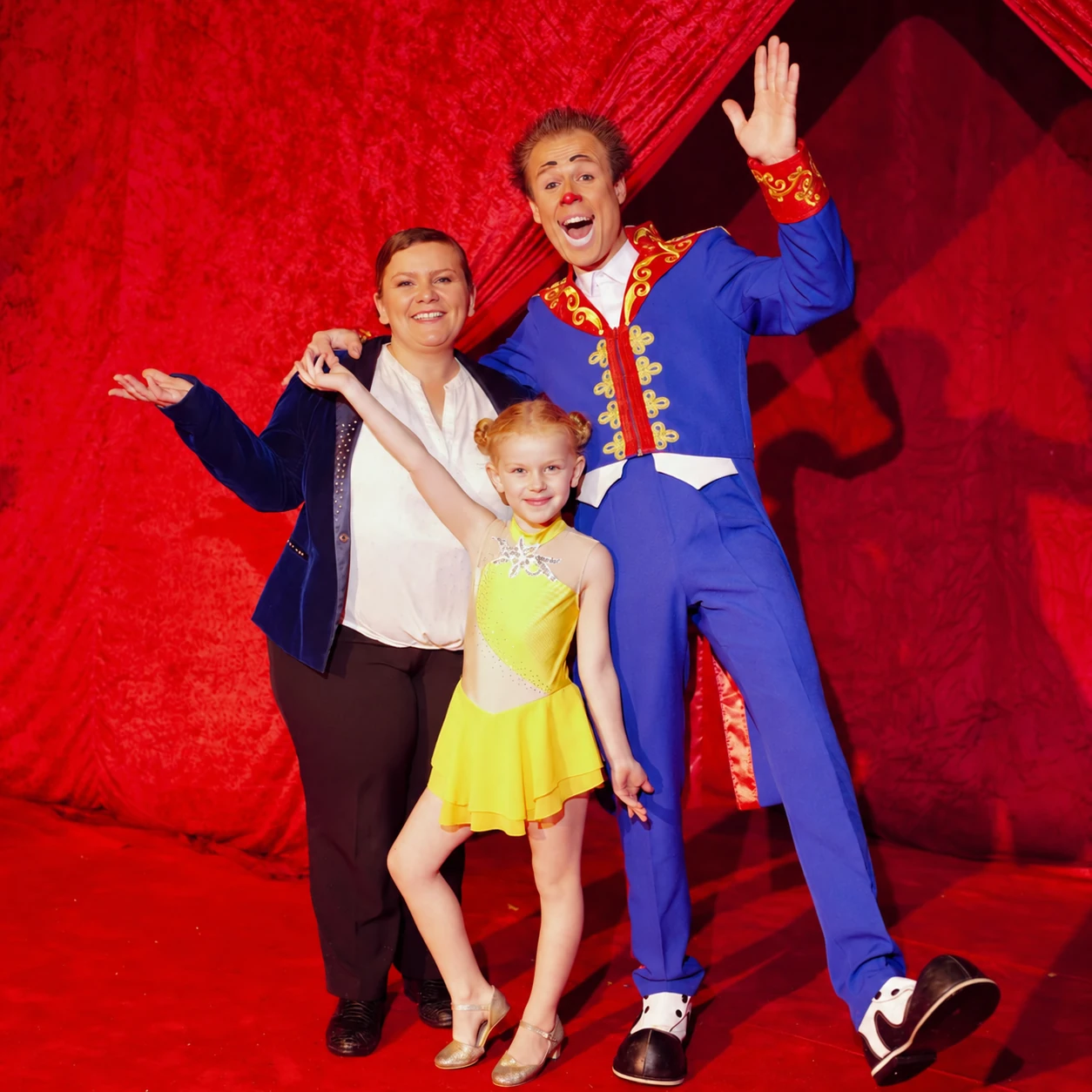 Les trois artistes de la compagnie Corbini devant les rideaux rouges du cirque.