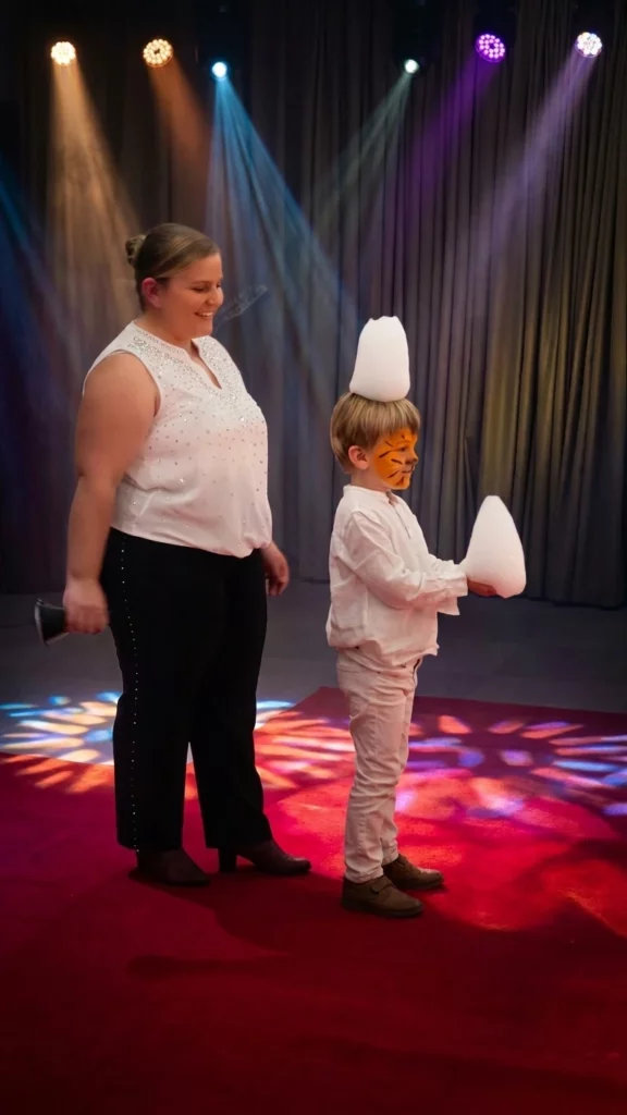 Un enfant sur scène avec de la mousse sur la tête et dans les mains.